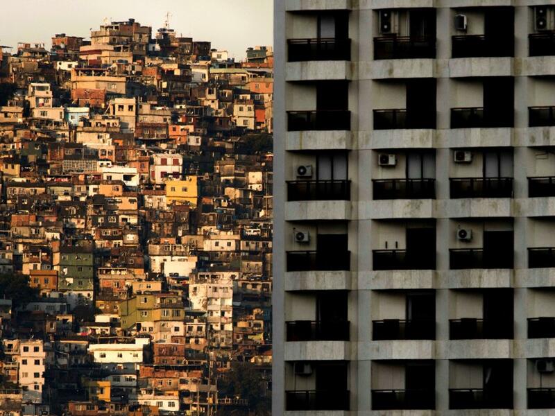 This file picture taken on September 27, 2017 shows a view of the Rocinha (L) favela seen behind a building of Sao Conrado neighbourhood, one of the richest areas of Rio de Janeiro. As the spread of the new coronavirus COVID-19 accelerates in Brazil, the poor populations crammed into the often unsanitary homes and precarious health services in the favelas, are on great alert. Mauro PIMENTEL / AFP