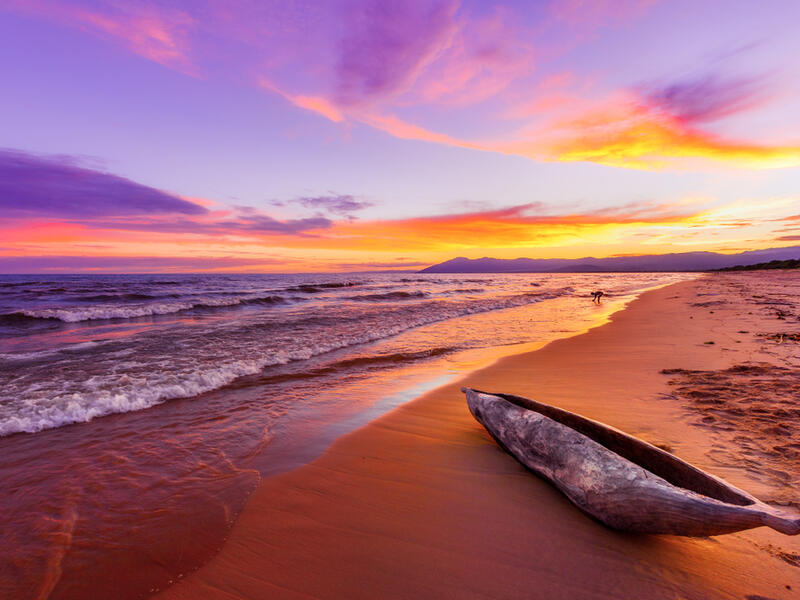 Lake Malawi sunset in Kande beach Africa, canoe boat on beach peaceful beach holiday beautiful sunset colors blue purple orange yellow in sky and clouds (Shutterstock)