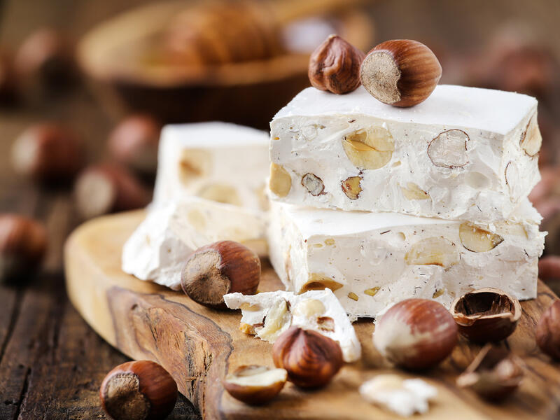 Delicious Italian festive torrone or nougat with hazelnuts on a wood (Shutterstock)