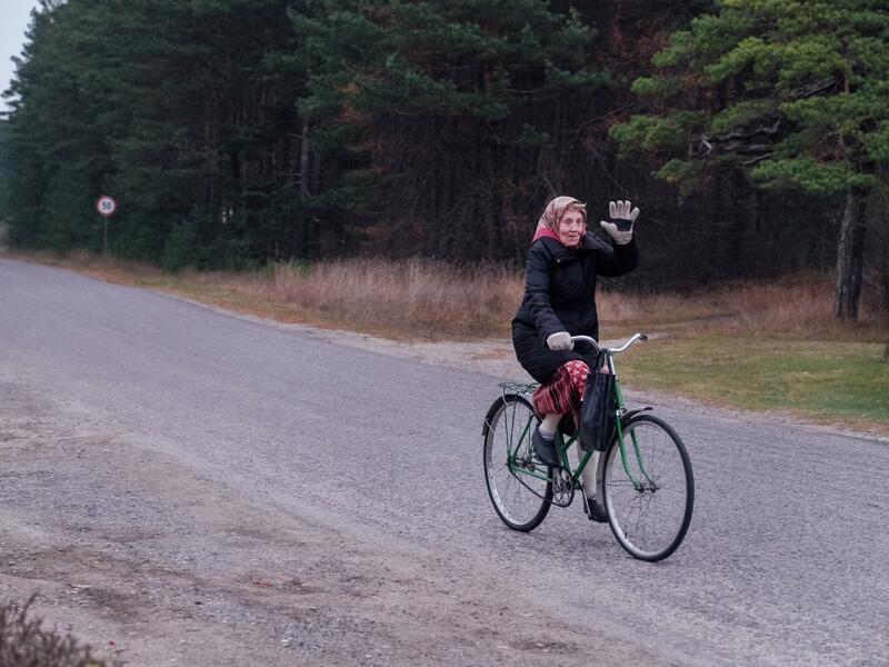 An elderly woman on her bicycle waves on November 20, 2019 on Kihnu island in the Baltic Sea, 10 kilometres (six miles) off the coast of Estonia. Steeped in folk traditions, Kihnu's historic way of life however is now threatened as economic hardship drives more and more islanders away in search of work. Alessandro RAMPAZZO / AFP