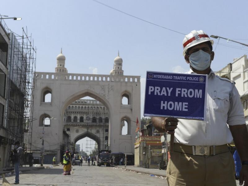 A traffic police personnel holds a placard on a deserted road during a one-day nationwide Janata (civil) curfew imposed as a preventive measure against the COVID-19 coronavirus, in Hyderabad on March 22, 2020. Nearly one billion people around the world were confined to their homes, as the coronavirus death toll crossed 13,000 and factories were shut in worst-hit Italy after another single-day fatalities record. NOAH SEELAM / AFP