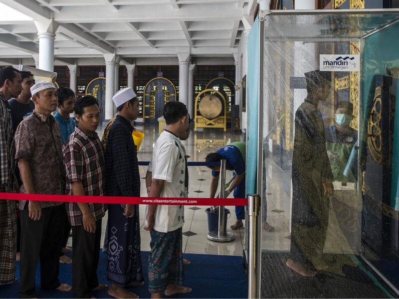 Indonesians walk through a disinfectant chamber before entering a mosque during Friday prayers in Surabaya, East Java on March 27, 2020, as a measure to stop the spread of the COVID-19 coronavirus. JUNI KRISWANTO / AFP