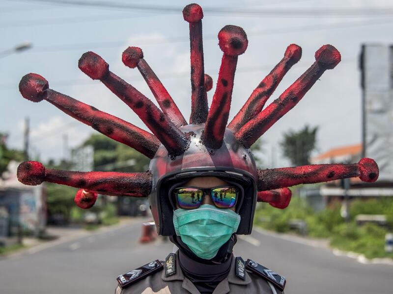 An Indonesian police officer wearing a Covid-19 coronavirus themed helmet conducts a campaign and disinfects motorists' vehicles in Mojokerto, East Java on April 3, 2020. Juni Kriswanto / AFP