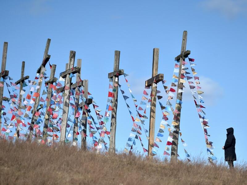 A man stands in front of giant crosses on April 5, 2020 in the town of Achmiany, some 130 km northwest of Minsk, during Palm Sunday celebrations which mark a week before Easter. Sergei GAPON / AFP
