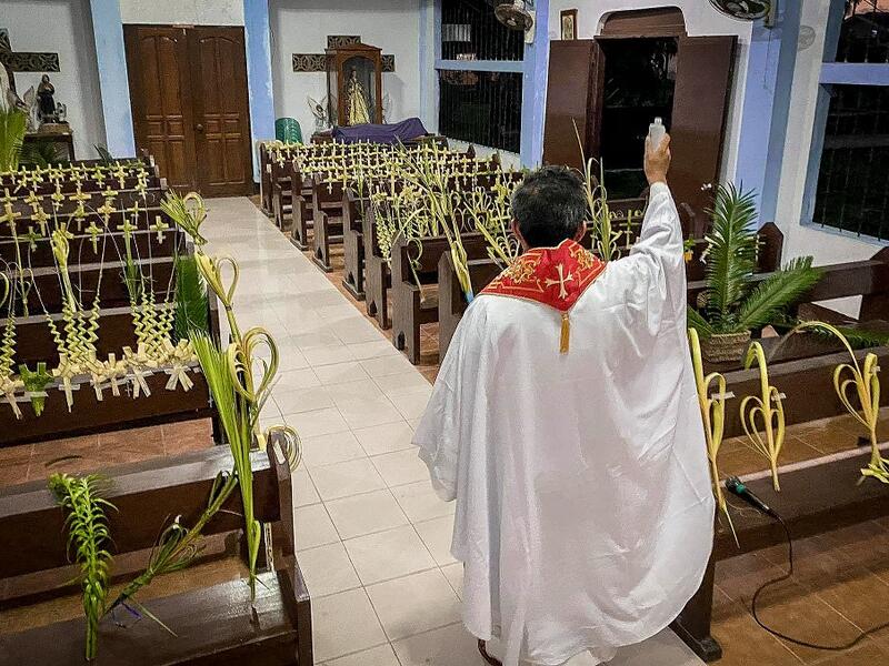 A Roman Catholic priest blesses palm branches occupying church pews during Palm Sunday event in Borongan town, Eastern Samar province, central Philippines on April 5, 2020. Alren BERONIO / AFP