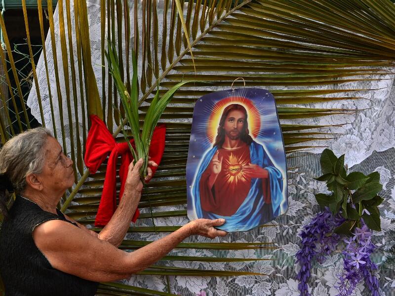 A woman prepares an altar at her house in Tegucigalpa on Palm Sunday on April 5, 2020, as all activities, including religious festivities during Holy Week, have been suspended under the curfew ordered by the Honduran government to help curb the spread of the novel coronavirus, COVID-19. More than 1.2 million cases, including 65,272 deaths, have been reported in 190 countries and territories around the world since the virus first emerged in China in December, according to an AFP tally compiled around 1100 GM