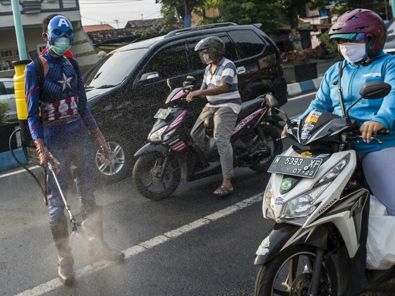 An Indonesian police officer wearing a superhero costume on the street disinfects motorists' vehicles in Pasuruan, East Java on April 9, 2020, amid concert to the COVID-19 coronavirus. JUNI KRISWANTO / AFP
