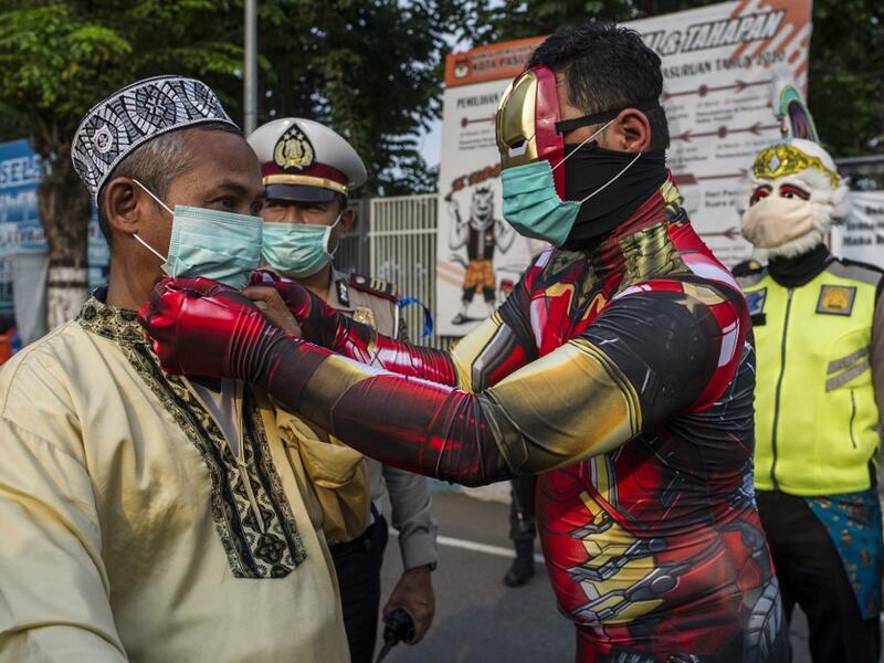Indonesian police officers wearing Indonesian superhero costumes on the street adjusts a face mask in Pasuruan, East Java on April 9, 2020, amid concert to the COVID-19 coronavirus. JUNI KRISWANTO / AFP