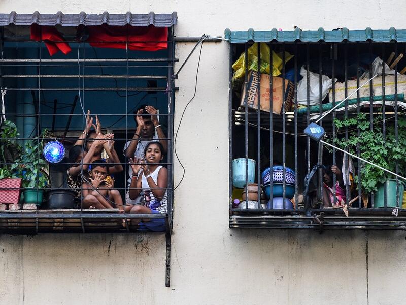 Residents watch from their flats' windows a music band formed by Sri Lankan Navy personnel as they play outside a housing complex during a government-imposed nationwide lockdown as a preventive measure against the COVID-19 coronavirus, in Colombo on April 9, 2020. ISHARA S. KODIKARA / AFP