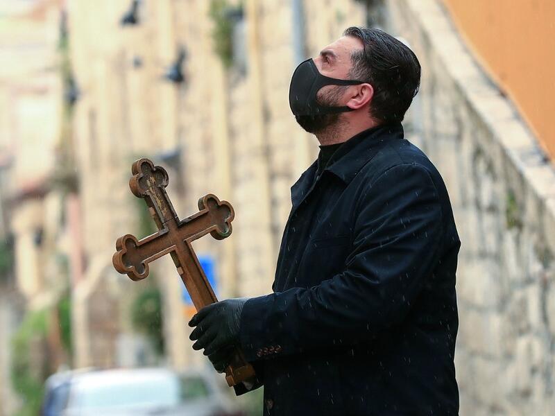 A Christian pilgrim wearing protective gear amid the COVID-19 outbreak, prays at the first station while making his way alone in the Procession of the Way of the Cross along the Via Dolorosa, to mark Good Friday in Jerusalem on April 10, 2020. All cultural sites in the Holy Land are shuttered, regardless of their religious affiliation, as authorities seek to forestall the spread of the deadly respiratory disease, which will prevent Christians from congregating for the Easter service, this coming Sunday for 