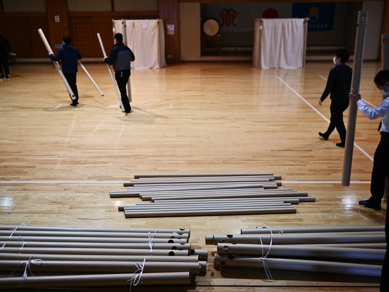 This photo taken on April 14, 2020 shows workers from Voluntary Architects' Network preparing to build a partition with cardboard pillars at a shelter provided by Kanagawa prefecture for people who can’t afford to rent an apartment and used to stay at designated internet cafes, which are closed due to the COVID-19 coronavirus outbreak state of emergency, at a judo sport hall in Yokohama, Kanagawa prefecture. CHARLY TRIBALLEAU / AFP
