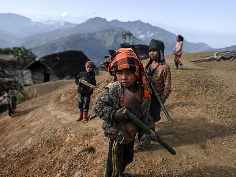 This photo taken on February 9, 2020 shows children playing in Karmawlawyi village in Myanmar's Sagaing region, near the border with India. The king of the Konyak tribe sleeps in Myanmar, but eats in India -- his house, village and people divided by a mountain border which serves as a vulnerable lifeline now severed by a coronavirus lockdown.  Ye Aung THU / AFP