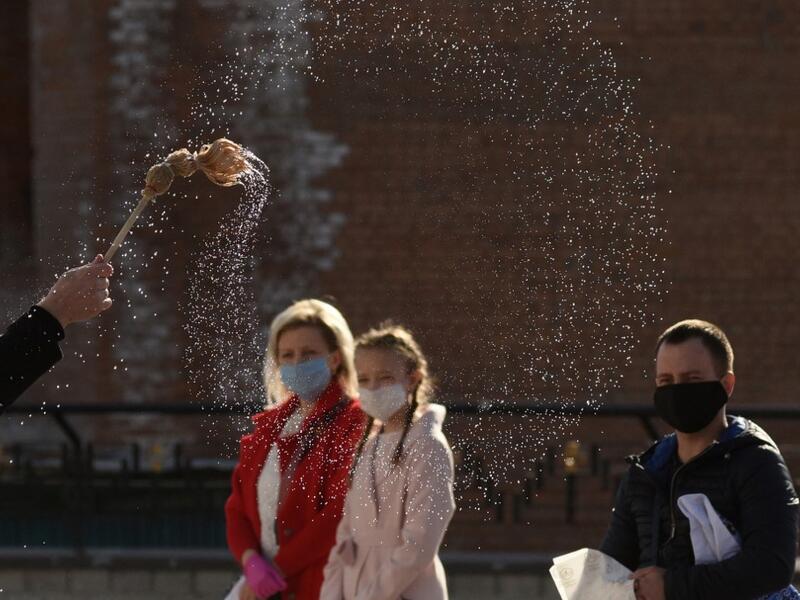 A priest of the Greek Catholic Church blesses believers wearing face masks as they keep social distance during the celebration of Orthodox Easter outside the Church of the Nativity of the Blessed Virgin, in western Ukrainian city of Lviv, on April 18, 2020, amid the COVID-19 pandemic caused by the novel coronavirus. Yuri DYACHYSHYN / AFP