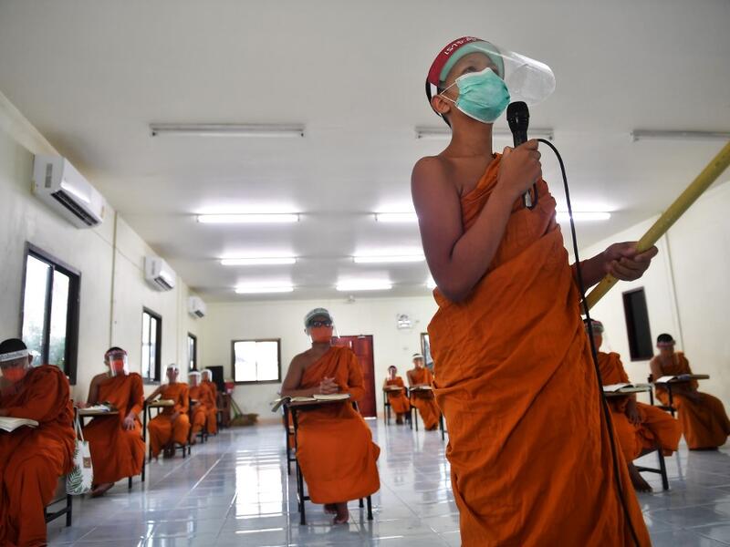 Novice monks wearing face shields as a preventive measure against the spread of the COVID-19 coronavirus attend religious studies at Wat Molilokkayaram Buddhist temple in Bangkok on April 20, 2020. Lillian SUWANRUMPHA / AFP