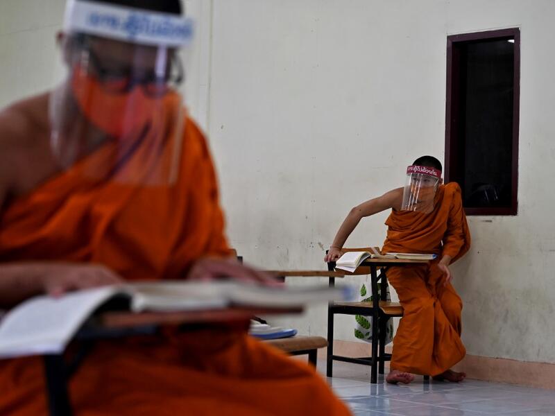 Novice monks wearing face shields as a preventive measure against the spread of the COVID-19 coronavirus attend religious studies at Wat Molilokkayaram Buddhist temple in Bangkok on April 20, 2020. Lillian SUWANRUMPHA / AFP