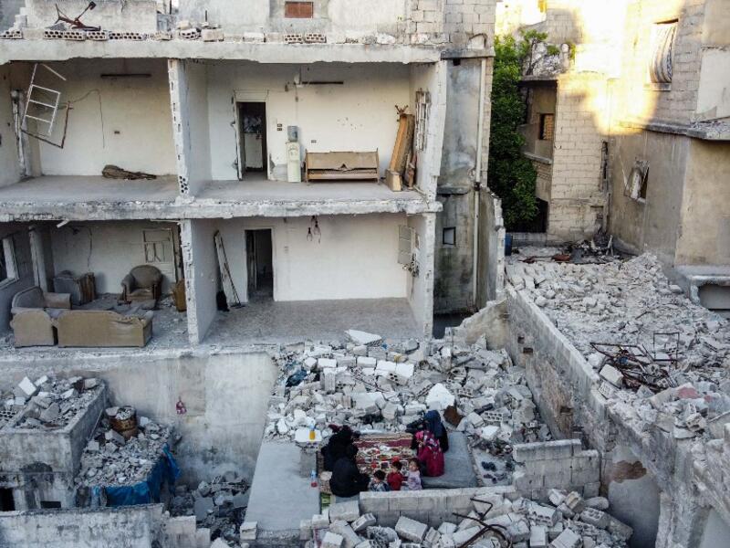 This picture taken on May 4, 2020 during the Muslim holy fasting month of Ramadan shows members of the displaced Syrian family of Tareq Abu Ziad, from the town of Ariha in the southern countryside of the Idlib province, breaking their fast together for the sunset "iftar" meal, in the midst of the rubble of their destroyed home upon their return to the town for one day after fleeing during the previous military assault by Syrian government forces and their allies. AAREF WATAD / AFP