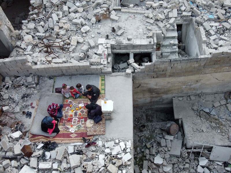 This picture taken on May 4, 2020 during the Muslim holy fasting month of Ramadan shows an aerial view of members of the displaced Syrian family of Tareq Abu Ziad, from the town of Ariha in the southern countryside of the Idlib province, breaking their fast together for the sunset "iftar" meal, in the midst of the rubble of their destroyed home upon their return to the town for one day after fleeing during the previous military assault by Syrian government forces and their allies. Aaref WATAD / AFP