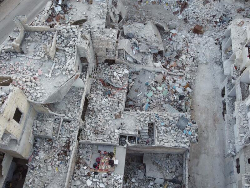 This picture taken on May 4, 2020 during the Muslim holy fasting month of Ramadan shows an aerial view of members of the displaced Syrian family of Tareq Abu Ziad, from the town of Ariha in the southern countryside of the Idlib province, breaking their fast together for the sunset "iftar" meal, in the midst of the rubble of their destroyed home upon their return to the town for one day after fleeing during the previous military assault by Syrian government forces and their allies. Aaref WATAD / AFP