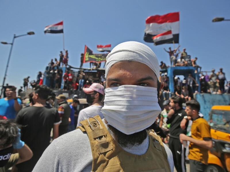 An Iraqi protester wears a face mask during an anti-government demonstration on Al-Jumhuriyah bridge in the capital Baghdad, on May 10,2020. Modest anti-government rallies resumed in some Iraqi cities today, clashing with security forces and ending months of relative calm just days after Prime Minister Mustafa Kadhemi's government came to power. AHMAD AL-RUBAYE / AFP