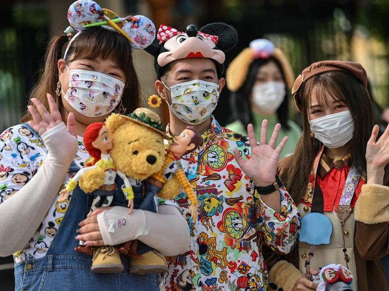People wearing face masks wait to enter the Disneyland amusement park in Shanghai on May 11, 2020. Disneyland Shanghai reopened on May 11 to the public after being closed since January due to the COVID-19 coronavirus outbreak. Hector RETAMAL / AFP