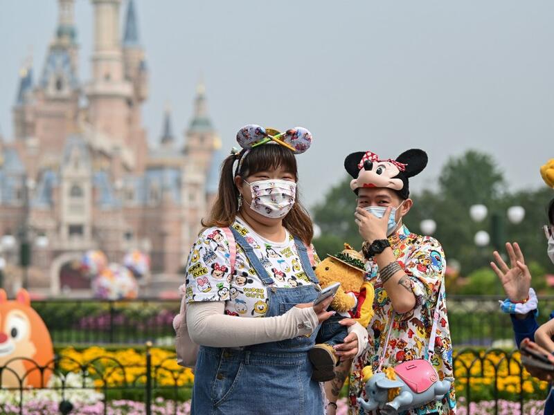 People wearing face masks visit the Disneyland amusement park in Shanghai on May 11, 2020. Disneyland Shanghai reopened on May 11 to the public after being closed since January due to the COVID-19 coronavirus outbreak. Hector RETAMAL / AFP