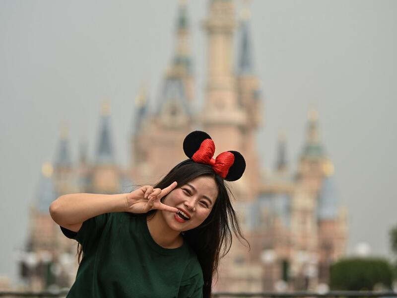 A woman gestures while visiting the Disneyland amusement park in Shanghai on May 11, 2020. Disneyland Shanghai reopened on May 11 to the public after being closed since January due to the COVID-19 coronavirus outbreak. Hector RETAMAL / AFP