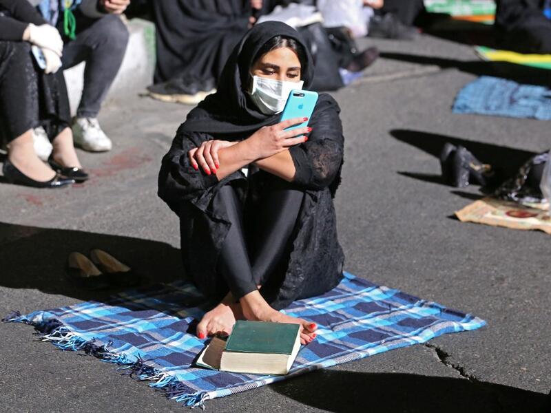 An Iranian woman wearing a face mask against the Covid-19 coronavirus attends Laylat al-Qadr prayers, one of the holiest nights during the Muslim fasting month of Ramadan, outside a mosque in the Tehran, on May 13, 2020. ATTA KENARE / AFP