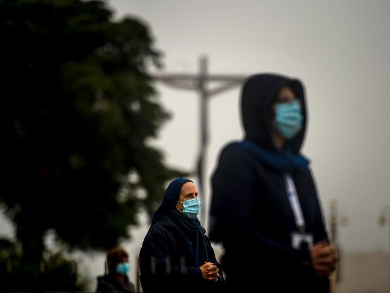 People wearing face masks and keeping their social distance, attend the 103rd anniversary of the apparitions of Our Lady of Fatima at the Fatima shrine in central Portugal on May 13, 2020. Without the crowd of pilgrims it welcomes every year, the shrine of Fatima celebrated the anniversary during a religious ceremony reduced to the bare minimum. PATRICIA DE MELO MOREIRA / AFP