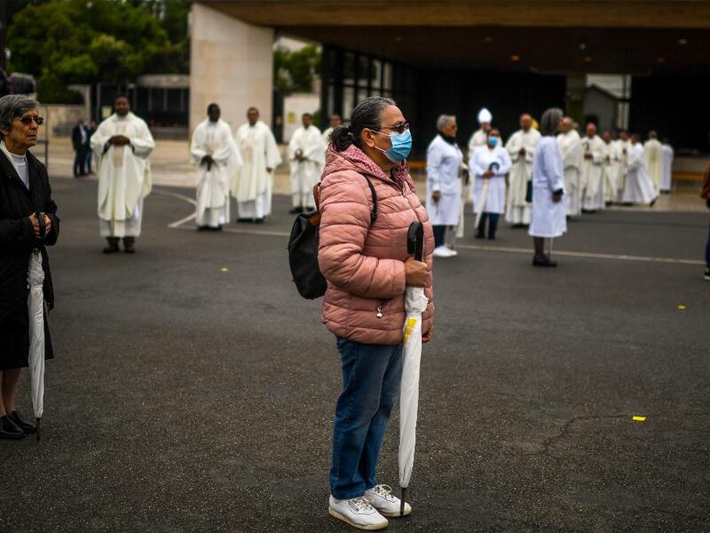 People attend a ceremony marking the 103rd anniversary of the apparitions of Our Lady of Fatima at the Fatima shrine in central Portugal, on May 13, 2020. Without the crowd of pilgrims it welcomes every year, the shrine of Fatima celebrated the anniversary during a religious ceremony reduced to the bare minimum. PATRICIA DE MELO MOREIRA / AFP