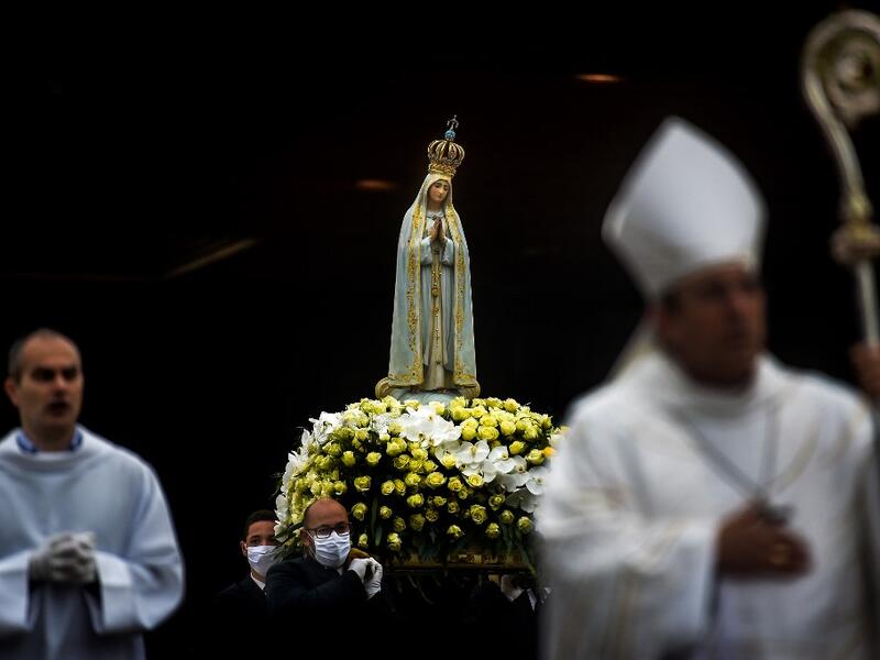 The statue of Our Lady Fatima is carried by people wearing face masks during the 103rd anniversary of the apparitions of Our Lady Fatima at the Fatima shrine in central Portugal on May 13, 2020. Without the crowd of pilgrims it welcomes every year, the shrine of Fatima celebrated the anniversary during a religious ceremony reduced to the bare minimum. PATRICIA DE MELO MOREIRA / AFP