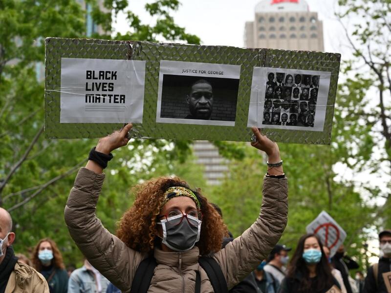 A woman is holding a Black Lives Matter placard asking for Justice for George and other victims of racism and police brutalities on Montreal's Place du Canada on May 31, 2020. Several thousands demonstrators marched on Sunday in central Montreal against racism and police violence, in solidarity with demonstrations in the United States following the death of George Floyd. Eric THOMAS / AFP
