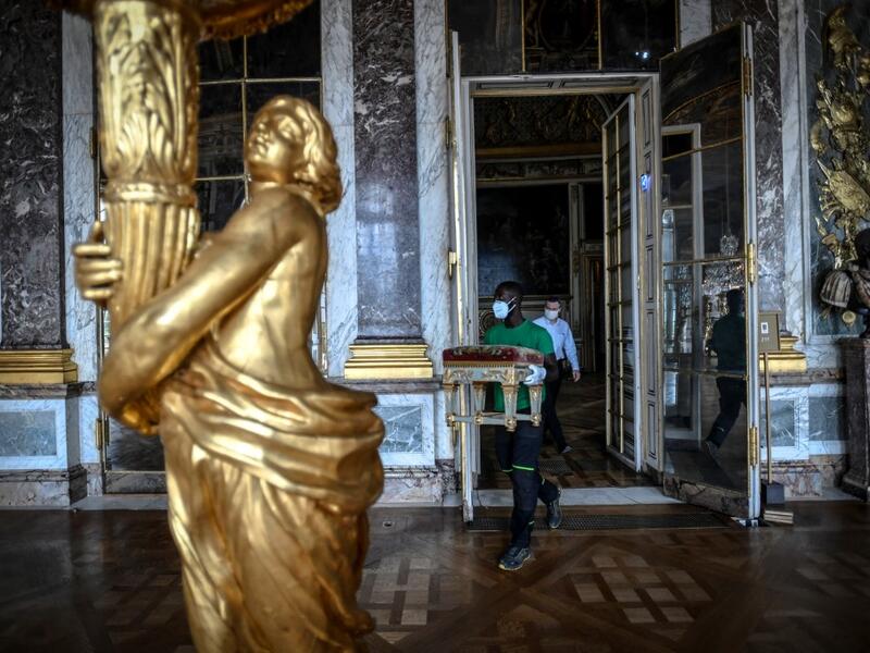 A worker carries furniture in the Galerie des Glaces (Hall of Mirrors) at the Chateau de Versailles (Palace of Versailles) in Versailles near Paris, on June 5, 2020 on the eve of it re-opening after 82 days of closure due to the novel coronavirus (COVID-19) outbreak. The Palace of Versailles -- France's big tourist attraction with nearly 10 million tourists a year - will open on June 6 with no US or Asia tourists who represent 30% of its visitors. STEPHANE DE SAKUTIN / AFP