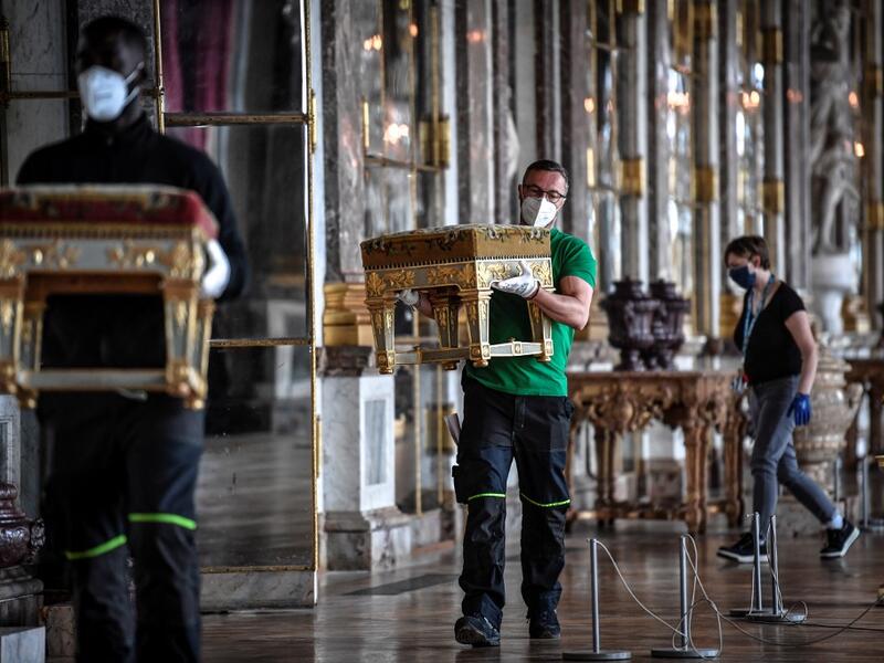 A worker carries furniture in the Galerie des Glaces (Hall of Mirrors) at the Chateau de Versailles (Palace of Versailles) in Versailles near Paris, on June 5, 2020, on the eve of it re-opening after 82 days of closure due to the novel coronavirus (COVID-19) outbreak. The Palace of Versailles -- France's big tourist attraction with nearly 10 million tourists a year - will open on June 6 with no US or Asia tourists who represent 30% of its visitors. STEPHANE DE SAKUTIN / AFP