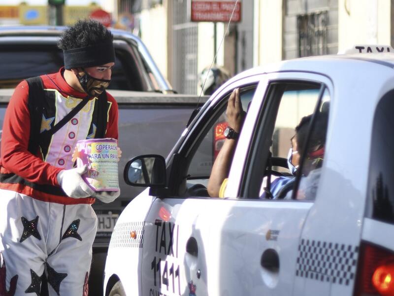 A clown begs for money to survive the crisis caused by the new coronavirus in Guatemala City, on June 9, 2020, as clowns have been unable to work due to restrictions to prevent the spread of the COVID-19.    Johan ORDONEZ / AFP