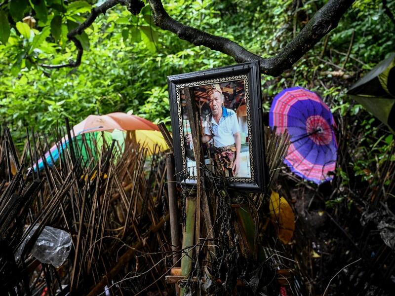 This picture taken on February 20, 2020 shows a photo of one of the deceased next to bamboo cages which cover bodies at a cemetery where Bali's Trunyanese people hold open-air burials - before restrictions were implemented due to the COVID-19 coronavirus - near the village of Trunyan in Bangli Regency, near Lake Batur on Bali island. SONNY TUMBELAKA / AFP