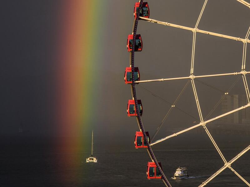 Passengers (top C) sit in a ferris wheel as a rainbow appears during sunset after a rain shower in Hong Kong on June 16, 2020. Anthony WALLACE / AFP