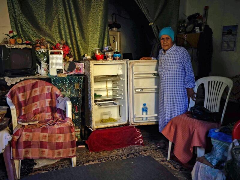 A Lebanese woman stands next to her empty refrigerator in her apartment in the port city of Tripoli north of Beirut on June 17, 2020. Lebanon's economic crisis has led to a collapse of the local currency and purchasing power, plunging whole segments of the population into poverty as exemplified by near-empty fridges in many households. IBRAHIM CHALHOUB / AFP