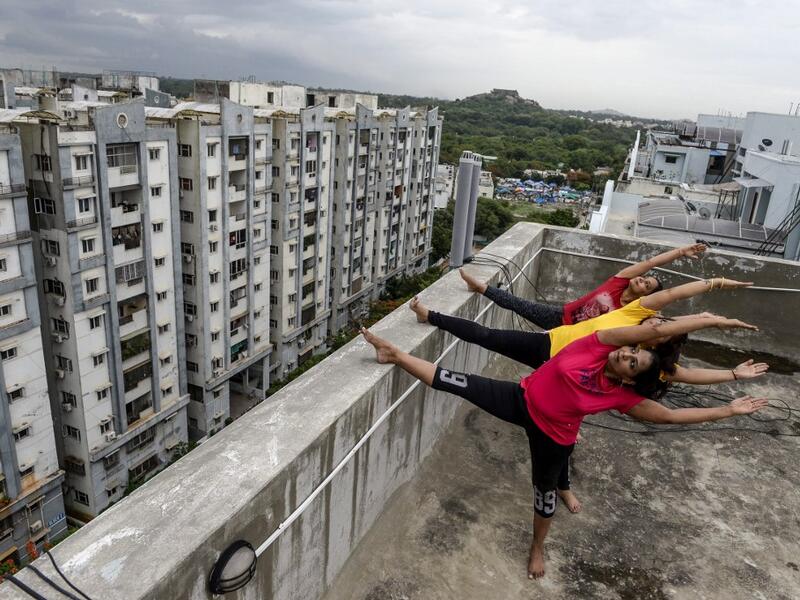 Yoga instructors from Anahata Yoga Zone perform yoga postures on a building's terrace in Hyderabad on June 18, 2020, ahead of the International Yoga Day annually celebrated on June 21. NOAH SEELAM / AFP