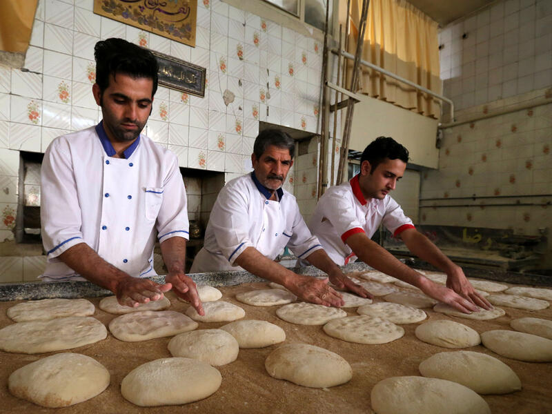 Iranian bakers Farzad Rabiei (L), 30, Esmail Asghari, 66, and Mojtaba Haydari, 23, prepare dough for Barbari bread in Tehran on June 7, 2020. ATTA KENARE / AFP