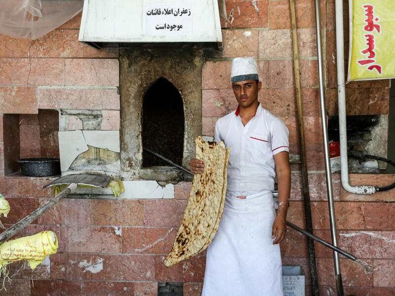 Ali, 21, an Iranian baker poses with Sangak bread in the capital Tehran on June 13, 2020. ATTA KENARE / AFP