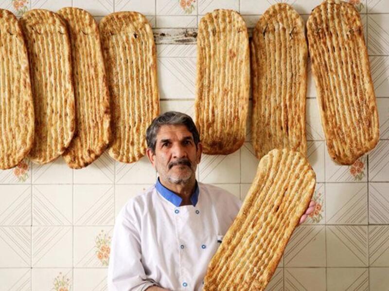 Iranian baker Esmail Asghari, 66, poses with Barbari bread in Tehran on June 7, 2020. ATTA KENARE / AFP