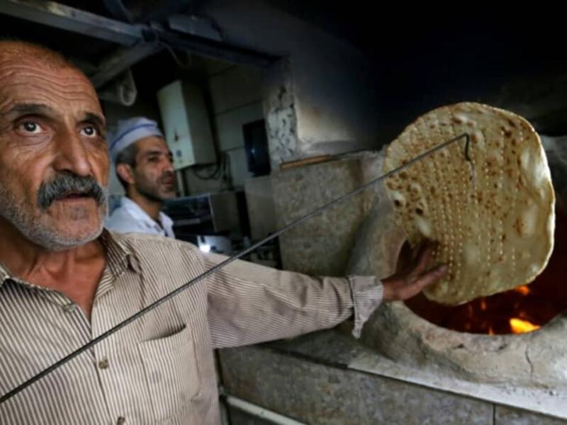 Iranian bakers Amir Jafari (L), 58, and Mohammad Mirzakhani, 41, make Taftoon bread in Tehran on June 13, 2020. ATTA KENARE / AFP