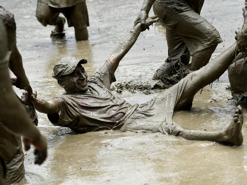Mud-covered farmers play in a rice paddy field during "National Paddy Day", which marks the start of the annual rice planting season, in Tokha village on the outskirts of Kathmandu on June 29, 2020. Splashing mud and drinking local rice beer, Nepali farmers this week celebrated National Paddy Day to mark the beginning of the rice-planting season, despite some coronavirus lockdown measures still in place. Traditional farming songs and laughter echoed in the air as farmers waded into waterlogged fields to sow