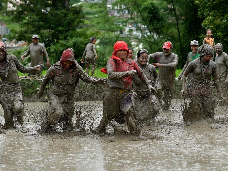 Mud-covered farmers play in a rice paddy field during "National Paddy Day", which marks the start of the annual rice planting season, in Tokha village on the outskirts of Kathmandu on June 29, 2020. PRAKASH MATHEMA / AFP