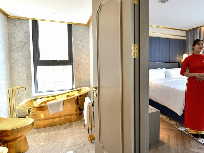 A staff member poses for a photograph inside the 1,000 USD per night executive two bedroom suite of the newly-inaugurated Dolce Hanoi Golden Lake hotel, the world's first gold-plated hotel, in Hanoi on July 2, 2020. Manan VATSYAYANA / AFP