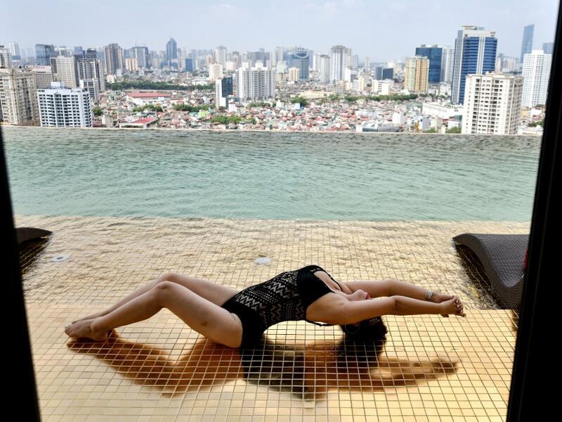 A guest poses for photographs at the infinity pool of the newly-inaugurated Dolce Hanoi Golden Lake hotel, the world's first gold-plated hotel, in Hanoi on July 2, 2020. Manan VATSYAYANA / AFP