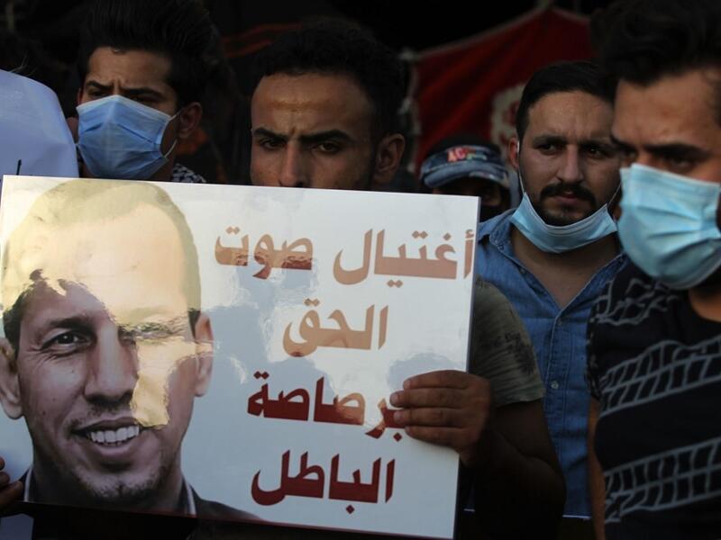 Iraqi demonstrators attend a symbolic funeral for slain Iraqi jihadism expert Hisham al-Hashemi, who was shot dead yesterday outside his house in the Iraqi capital, on July 7, 2020 at Baghdad's Tahrir square. Slogan reads in Arabic: "the voice of right killed with the bullet of wrong". The killing of the 47-year-old prominent expert has stirred fears Iraq is entering a dark and violent phase, as boiling tensions between pro-Iran factions and the government reach new heights. AHMAD AL-RUBAYE / AFP