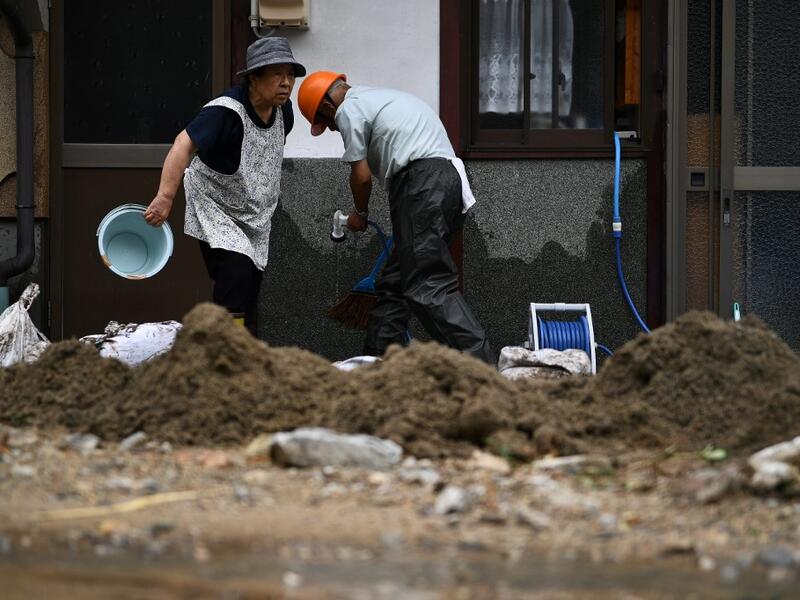 People clear debris and mud outside their home following heavy rains and flooding in the village of Gero, Gifu prefecture on July 9, 2020. Japanese emergency services and troops were scrambling to reach thousands of homes cut off by devastating flooding and landslides that have killed dozens and caused widespread damage. Philip FONG / AFP