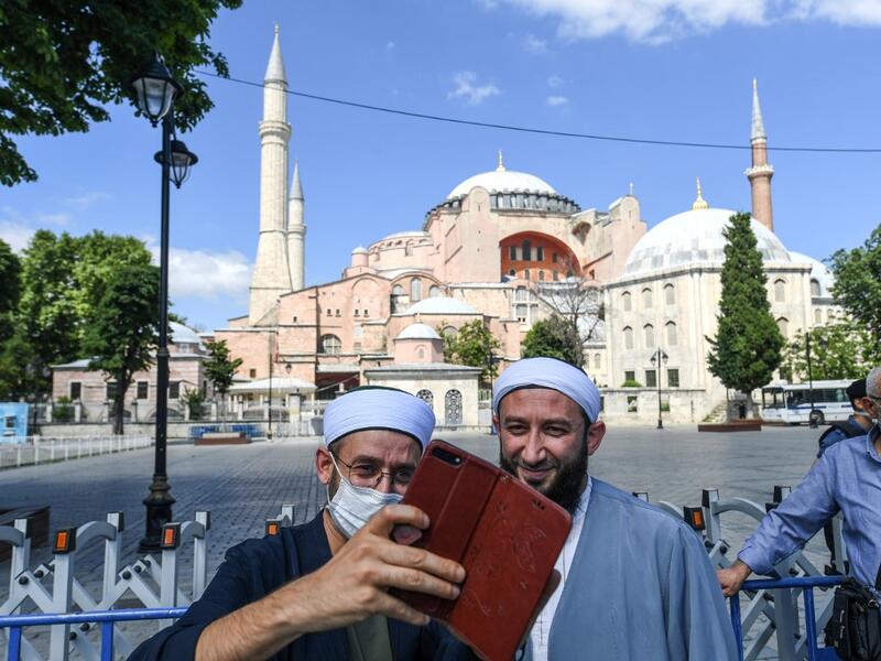 Two men take a selfie picture in front of Hagia Sophia on July 11, 2020 in Istanbul, a day after a top Turkish court revoked the sixth-century Hagia Sophia's status as a museum, clearing the way for it to be turned back into a mosque. The World Council of Churches, which represents 350 Christian churches, said on July 11 it wrote to Turkey's President expressing "grief and dismay" over his decision to turn the Hagia Sophia back into a mosque. Ozan KOSE / AFP