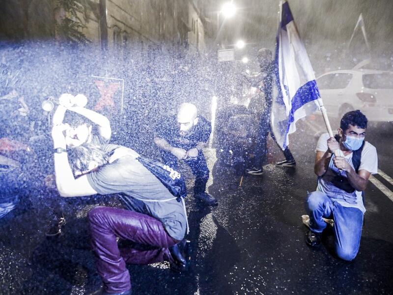 Israeli police spray protesters (clad in masks due to the COVID-19 coronavirus pandemic) with water cannon during an anti-government demonstration in Jerusalem, on July 18, 2020. Ahmad GHARABLI / AFP